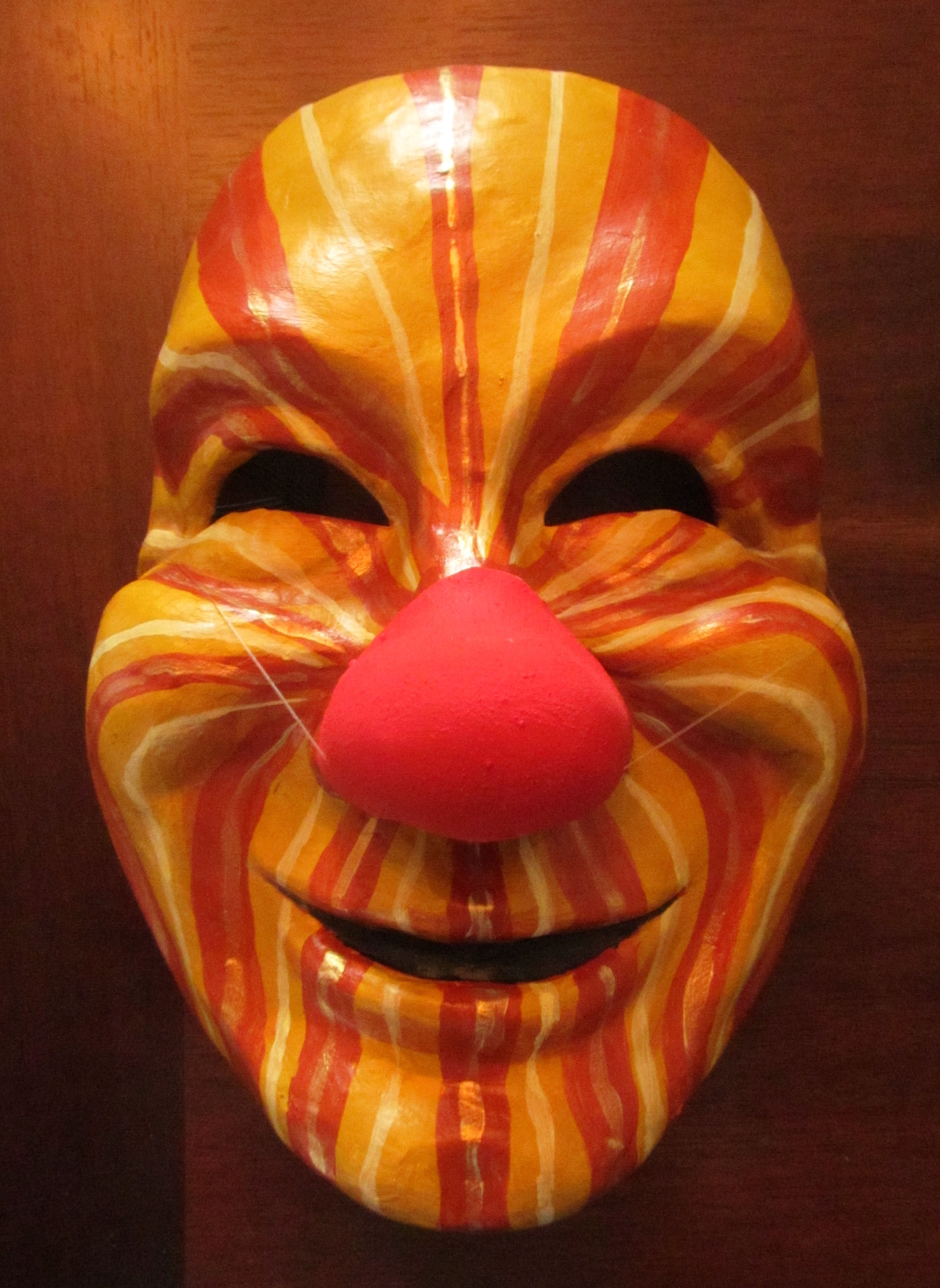 The mask is painted so that the rays of the sun emanate from the nose of the clown, spreading warmth and joy.